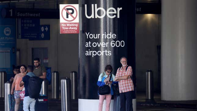 Passengers wait near Uber ride-share signage after arriving at Los Angeles International Airport (LAX) in Los Angeles, California, U.S. July 10, 2022.