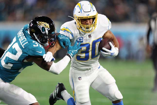 Jan 14, 2023; Jacksonville, Florida, USA; Los Angeles Chargers running back Austin Ekeler (30) is tackled by Jacksonville Jaguars cornerback Tyson Campbell (32) during the first quarter of a wild card game at TIAA Bank Field.