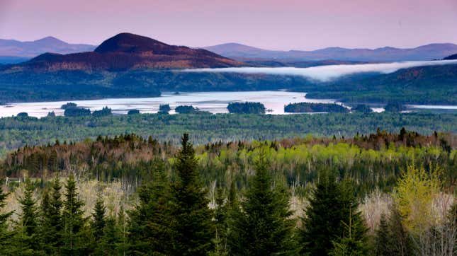 A view of Attean Pond near Jackman, Maine, with mountains in the background and fog over a valley below.