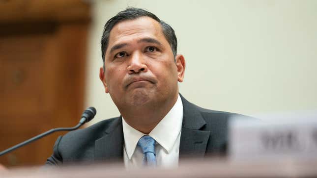 A middle-aged man in a suit frowns during a Congressional hearing.