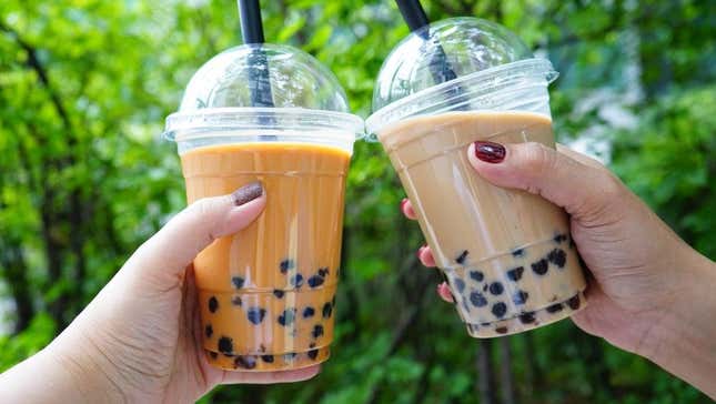 Two cups of bubble tea with boba held up as a toast