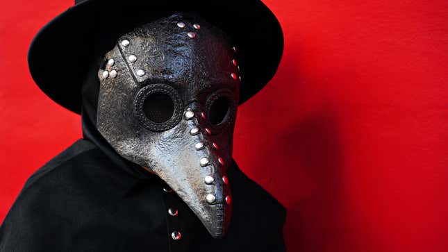 A person dressed in a plague mask and black hat, standing against a red background