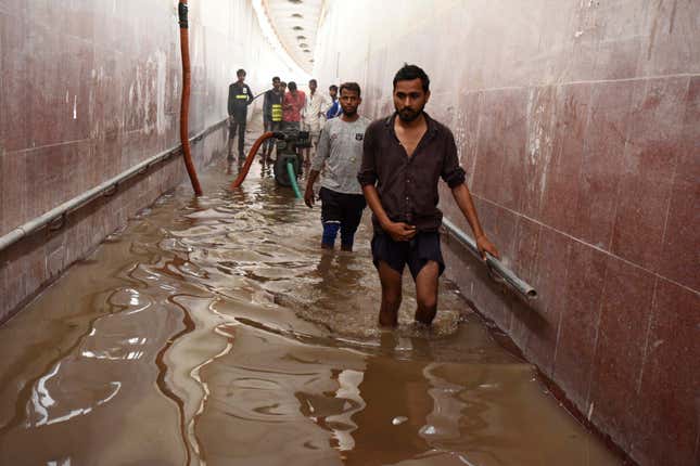 People wade across a waterlogged pedestrian subway, at National  Highway-48, in Kherki Daula near the police station on August 13,  2020 in Gurugram, India.