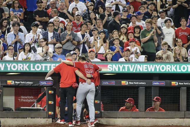 Aug 26, 2023; New York City, New York, USA;  Los Angeles Angels starting pitcher Chase Silseth (63) is helped back into the dugout after getting hit in the head by a throw in the fourth inning against the New York Mets at Citi Field.