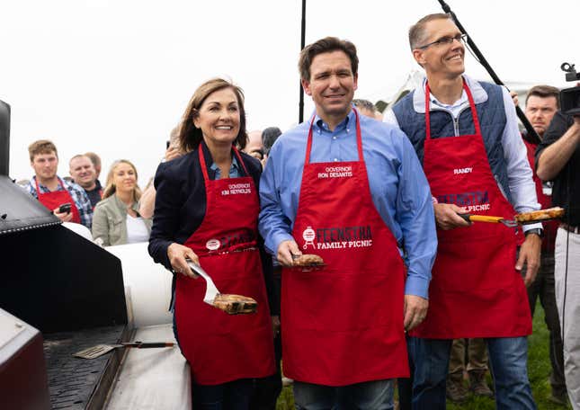 From left, Iowa Gov. Kim Reynolds, Florida Gov. Ron DeSantis and Congressman Randy Feenstra flip meat on the grill for a photo op during the annual Feenstra Family Picnic in Sioux Center, Iowa, on May 13, 2023.