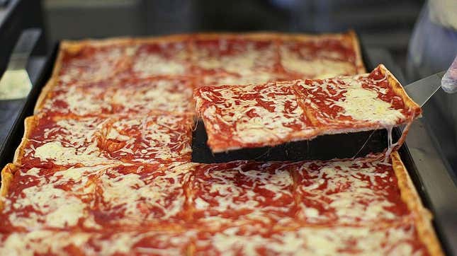 A spatula lifts a square slice of thin crust pizza from a rectangular pan