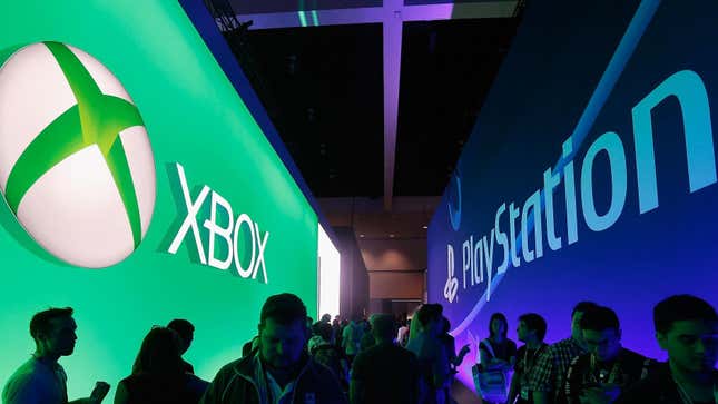 People walk past opposing Xbox and PlayStation logos at E3.