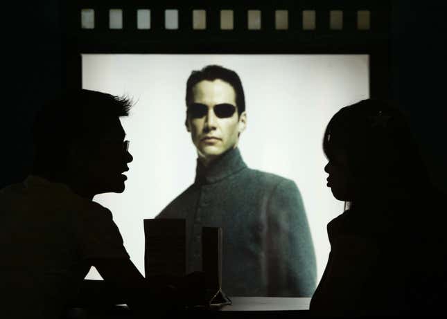 Movie seen in silhouette in front of Hollywood star Keanu Reeves poster in the movie Matrix Reloaded 