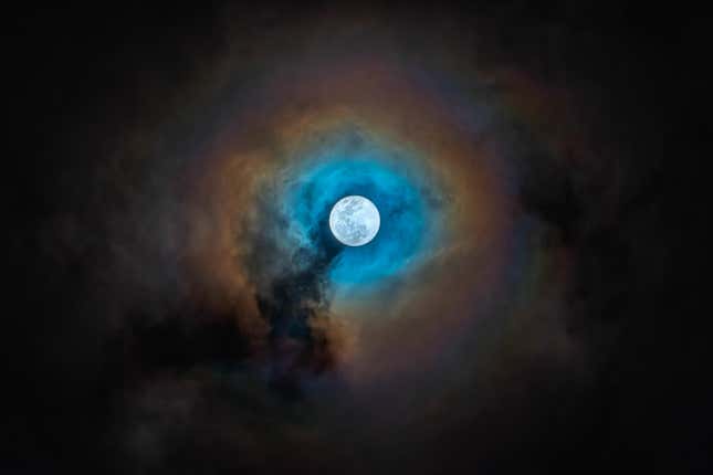 The Moon shines through clouds in Earth's skies.