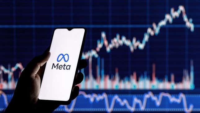 The Meta logo on a phone in front of stock charts