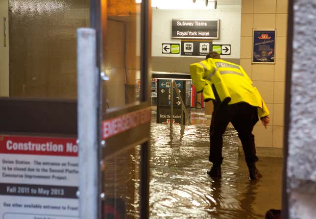 A Toronto police officer leans over to inspect a flooded Union Station Subway in Toronto on Friday, June 1, 2012. 