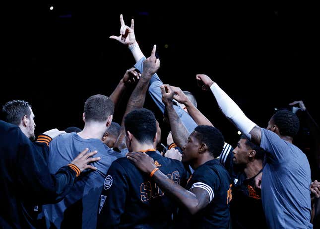 The Phoenix Suns, still dressed in pregame warmups, raise their fists in the air in a huddle before the start of an NBA game.