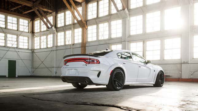 A photo of a white Dodge Charger in a warehouse. 