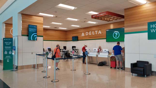 Customers wait in line at the Delta customer service counter at an airport