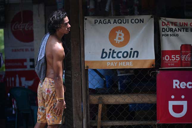 A man standing outside a shop in El Salvador that accepts bitcoin.