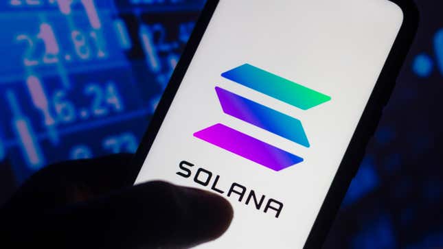 A silhouette holds the Solana logo on a smartphone amid a backdrop of stock numbers.
