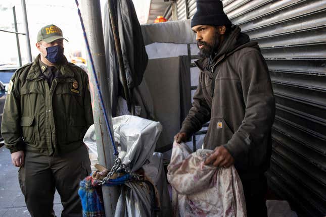 A sanitation worker talks to Neil Singh, a homeless man who has been living on Eldridge street for almost two years, as he is forced to dismantle his structure and move after receiving a notice from the city Department of Sanitation as part of Mayor Adams policy to remove homeless encampments, April 11, 2022, in the Chinatown neighborhood of New York City, New York. 