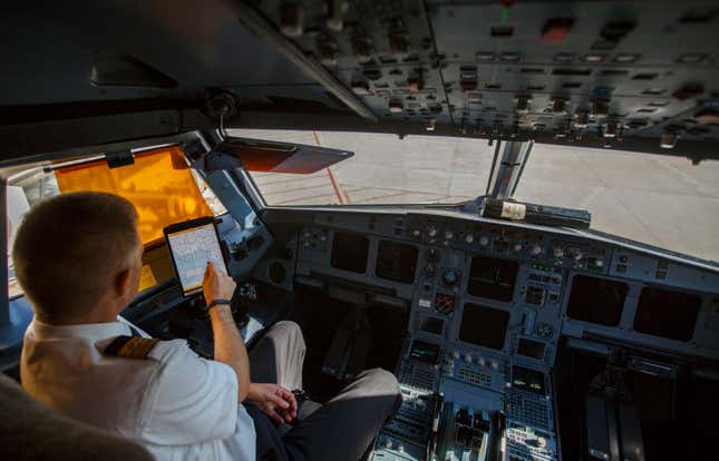 An Iberia Airlines pilot touches the screen of an iPad during a demonstration inside a cockpit of a passenger plane at Terminal 4 of Madrid's Adolfo Suarez Barajas airport