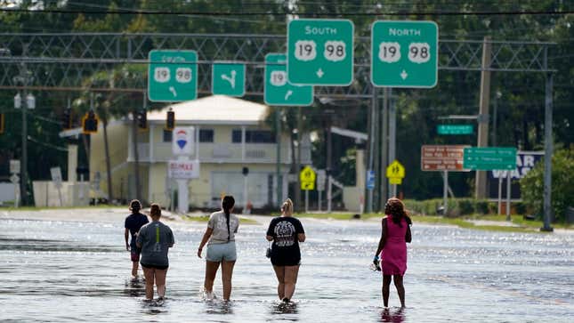 People walk through flood waters on SR44 on August 30, 2023, in Crystal River, Florida after Hurricane Idalia made landfall earlier. 