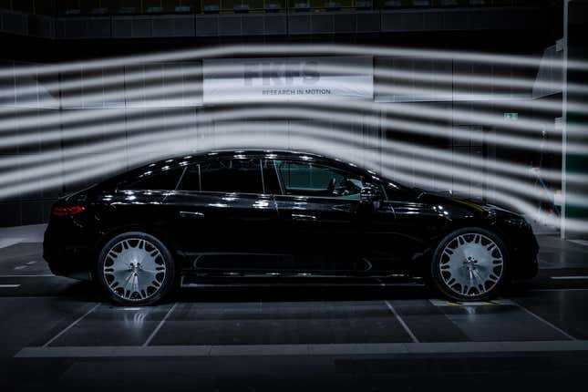 A black electric sedan with gaudy, gigantic wheels sits in a wind tunnel being sleek.