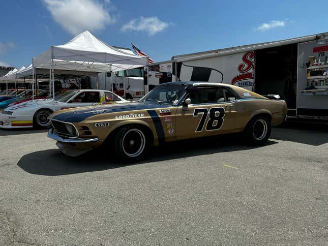 A gold Ford Mustang Boss Trans-Am car is parked in the pits at Laguna Seca