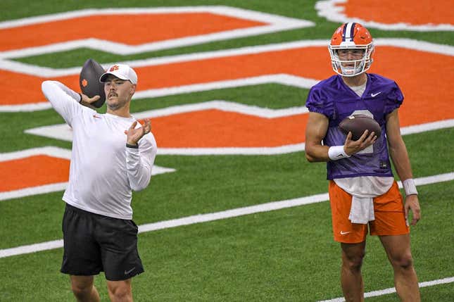 Clemson offensive coordinator Garrett Riley passes a ball while quarterback Cade Klubnik (2) watches during preseason practice at the Poe Indoor Practice Facility at the Allen N. Reeves football complex in Clemson, S.C. Monday, August 7, 2023.