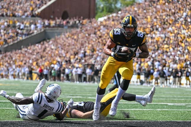 Sep 2, 2023; Iowa City, Iowa, USA; Iowa Hawkeyes tight end Erick All (83) scores on a touchdown pass as Utah State Aggies safety Anthony Switzer (1) and Iowa tight end Steven Stilianos (86) lay on the turf during the first quarter at Kinnick Stadium.