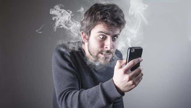 An angry man with smoke coming out of his nose looks at a phone