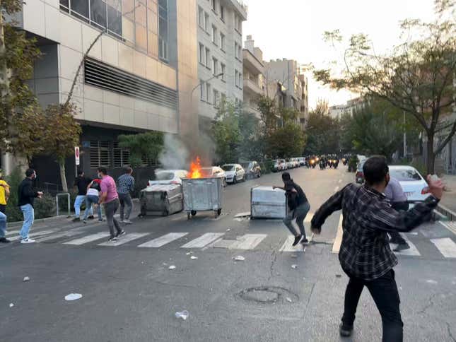 In this Tuesday, Sept. 20, 2022, photo taken by an individual not  employed by the Associated Press and obtained by the AP outside Iran,  protesters throw stones at anti-riot police during a protest over the  death of a young woman who had been detained for violating the country’s  conservative dress code, in downtown Tehran, Iran.