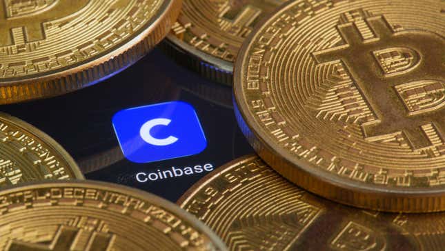 Coinbase logo on a computer screen surrounded by gold Bitcoin coins
