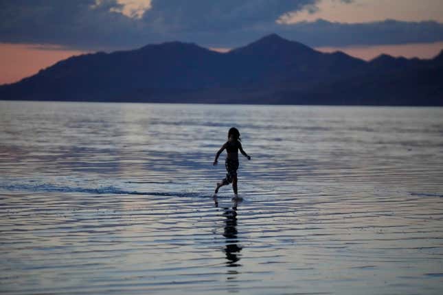 FILE - A young person runs through the Great Salt Lake on June 15, 2023, near Magna, Utah. A coalition of environmental organizations sued the state of Utah on Wednesday, Sept. 6, 2023, based on accusations that it is not doing enough make sure enough water gets to the shrinking Great Salt Lake. (AP Photo/Rick Bowmer, File)