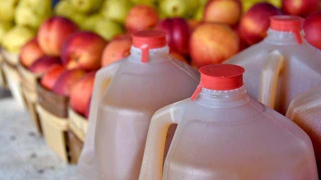 jugs of apple cider beside apples