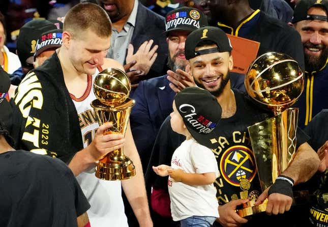 Jun 12, 2023; Denver, Colorado, USA; Denver Nuggets center Nikola Jokic (15) celebrates with the Bill Russell NBA Finals MVP Award as guard Jamal Murray (27) holds the Larry O&#39;Brien Trophy after the Nuggets won the 2023 NBA Championship against the Miami Heat at Ball Arena.