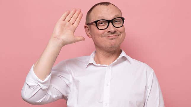 A man in a white shirt smiles and waves goodbye. 