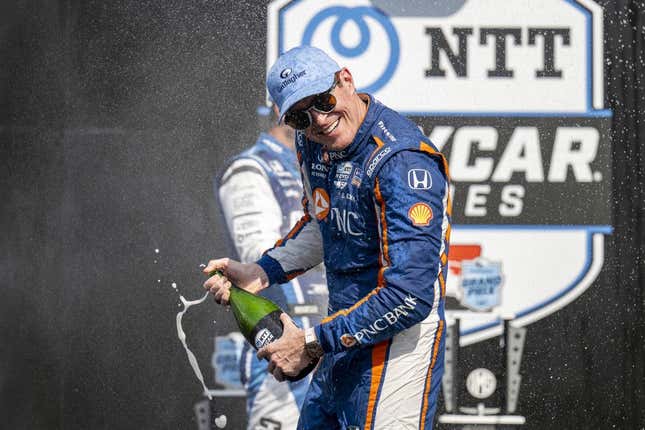 Aug 12, 2023; Speedway, Indiana, USA; Chip Ganassi Racing driver Scott Dixon (9) turns away from Rahal Letterman Lanigan Racing driver Graham Rahal (15) during the champagne fight on the podium after the Gallagher Grand Prix at the Indianapolis Motor Speedway Road Course.