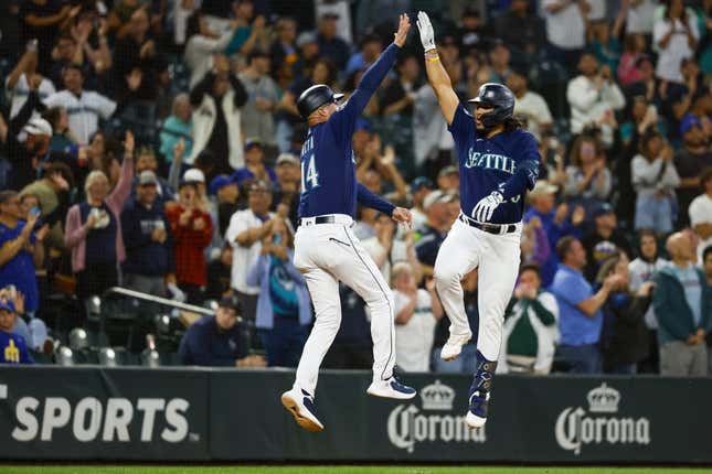 Jul 17, 2023; Seattle, Washington, USA; Seattle Mariners third baseman Eugenio Suarez (28) makes a jumping high-five with third base coach Manny Acta (14) while running the bases after hitting a two-run home run against the Minnesota Twins during the seventh inning at T-Mobile Park.