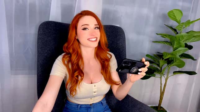 Amouranth is sitting in a black chair with a green plant flanking her right, talking about about cosplay in a July 2022 YouTube video.