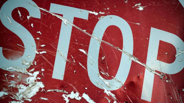 Close-up of a red stop sign after a traffic accident. The sign is heavily scratched and dented.