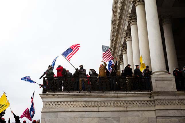A group of pro-Trump protesters wave flags from a platform on the Capitol Building on January 6, 2021 in Washington, DC. A pro-Trump mob stormed the Capitol, breaking windows and clashing with police officers.