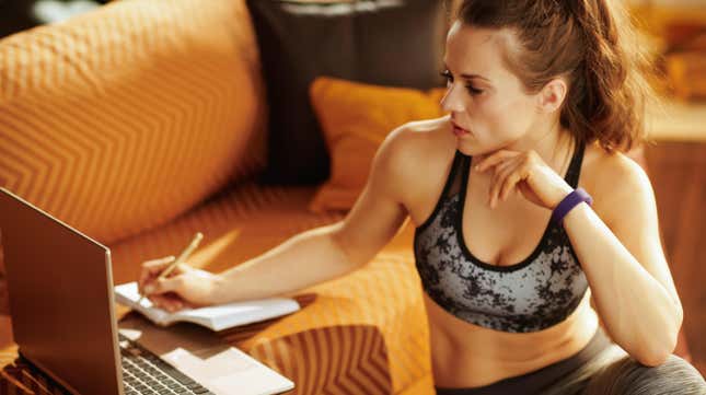 woman wearing workout clothes, writing in a training journal