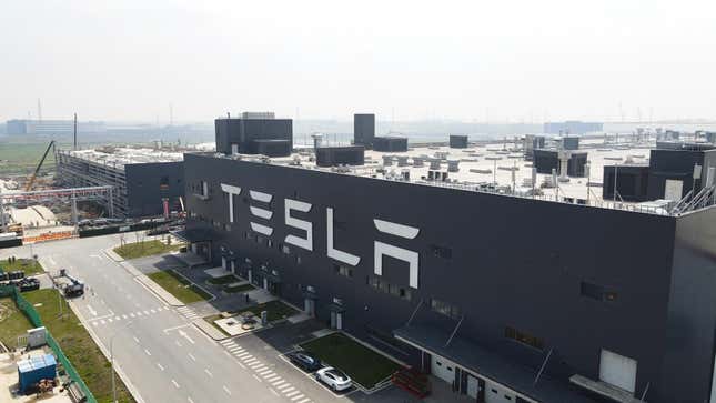 A large building with the Tesla Logo on the side and an empty street in front.
