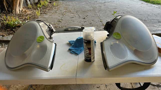 A pair of sanded and prepped headlights are on a table waiting to be painted.