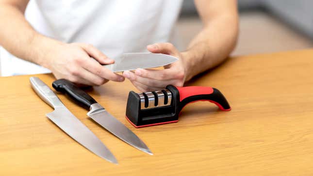 A man with three knives and a pull-through sharpener.