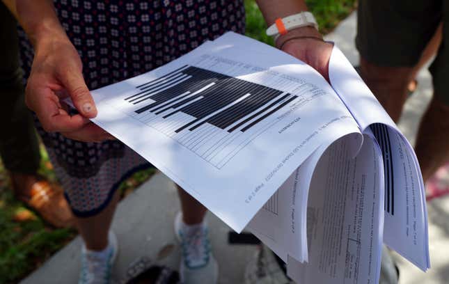 Journalists gather outside the Paul S. Rogers Federal Building and U.S. Courthouse in downtown West Palm Beach, Fla., to read a heavily blackout document released by The Justice Department Friday, Aug. 26, 2022.