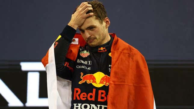 Max Verstappen, draped in a flag, his hand on his head.
