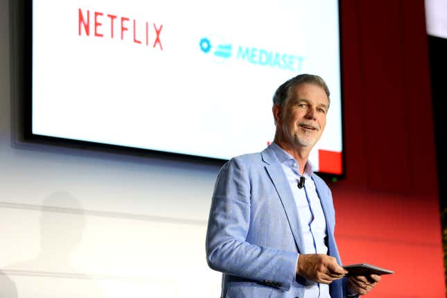 Netflix co-CEO Reed Hastings stands with a tablet in front of a screen reading Netflix and Mediaset.
