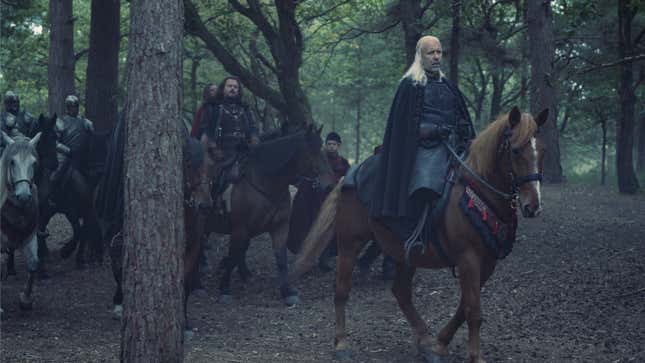 King Viserys rides on a brown horse through the forest, his massive retinue trailing behind him.