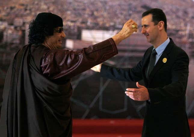 Assad greets Libya’s Muammar Gaddafi, a fellow dictator imperiled by Bush’s democracy promotion.