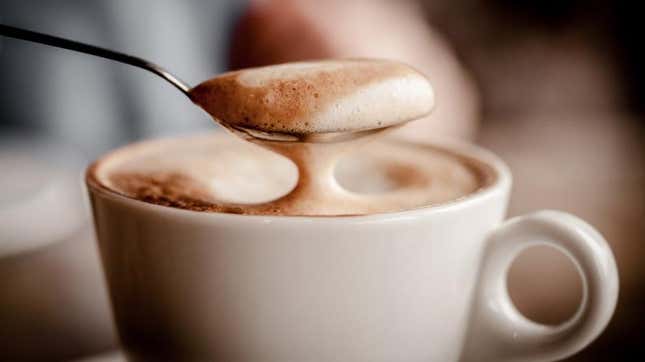 Spooning latte foam over coffee cup