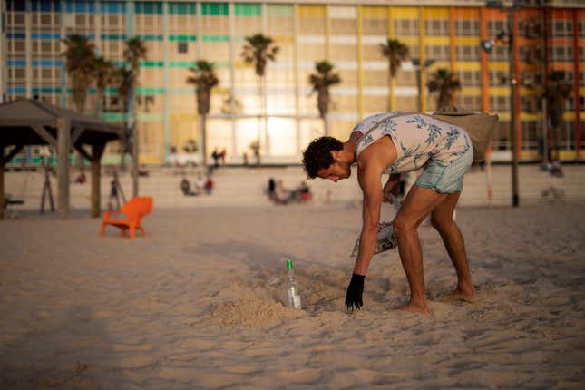 Julian Melcer collects cigarette butts from the shore of the Mediterranean Sea as part of his environmental campaign at a beach in Tel Aviv, Israel